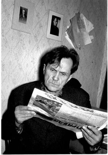 Шаламов читает газету. На стене – фотография Осипа Мандельштама. 1968 год